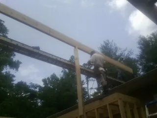 Carpenter setting a ridge beam over a new addition frame — Ice Dam Removal by Roofing Brothers in Treadwell
