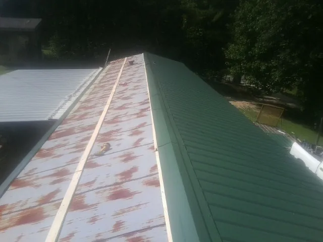 Old rusted panels beside newly installed green metal roofing — Wind Damage Roof Repair by Roofing Brothers in Treadwell