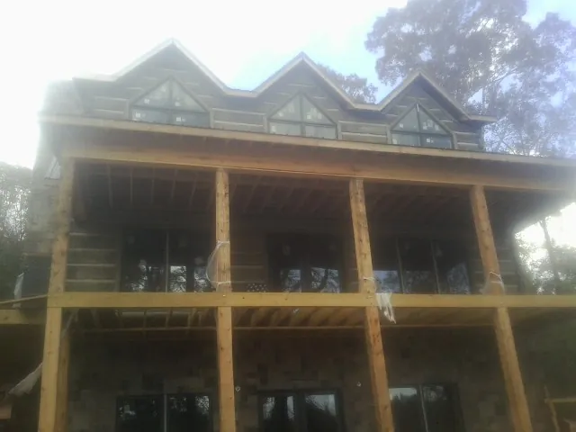 Dormers and porch framing on a large log home under construction — Roof Coating work by our crew in Treadwell