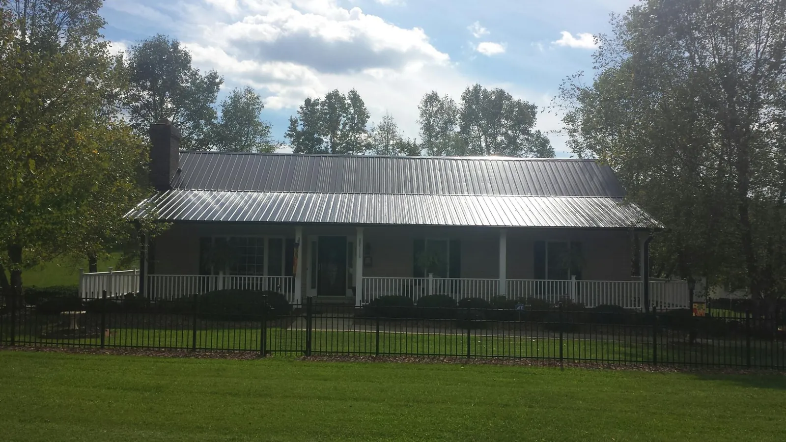 Gray metal roof on a brick ranch with a full width front porch — Gutter Guard Installation work by our crew in Treadwell
